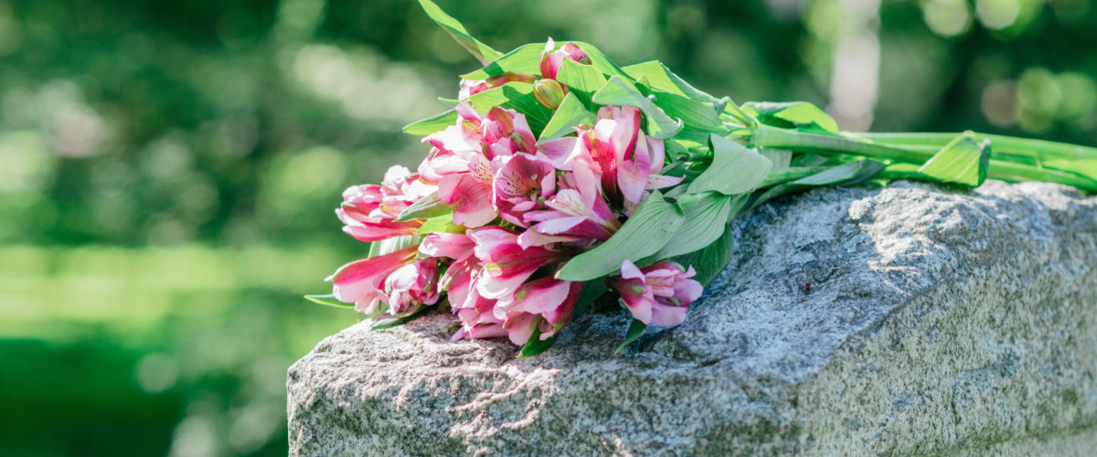pink and white flowers resting on a gravestone 2